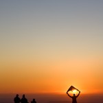 Man launching a kite at sunset